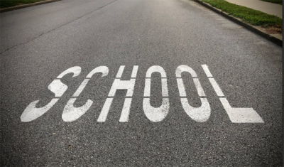 : An image of a school warning sign on a road.